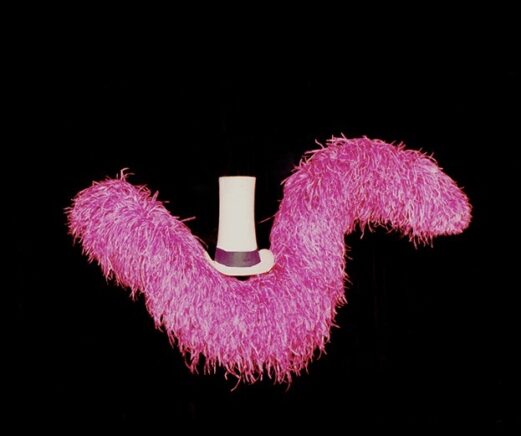 Un boa de plumes rose et un chapeau haut-de-forme argenté sur un fond noir