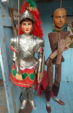 Photographie de deux pupi en bois, une vêtue d'une armure colorée et l'autre dévêtue.