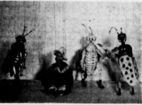 Photographie où l'on voit des marionnettes à fils représentant des insectes à forme humanoïde, menaçants.