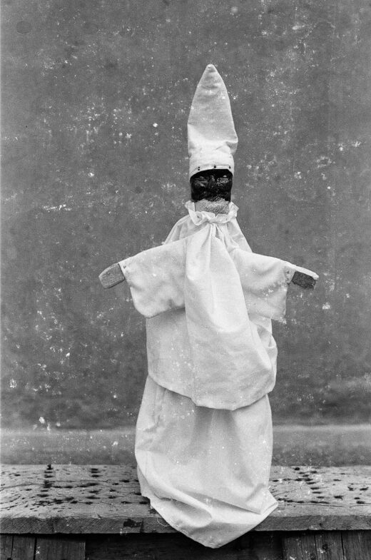 Petite marionnette à gaine de Pulcinella avec son grand costume blanc, son masque noir et son long chapeau pointu.