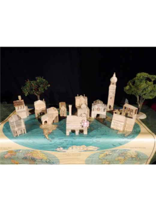 Photographie représentant une maquette d'une petite ville typique d'Italie posée sur une carte du monde sur une table.