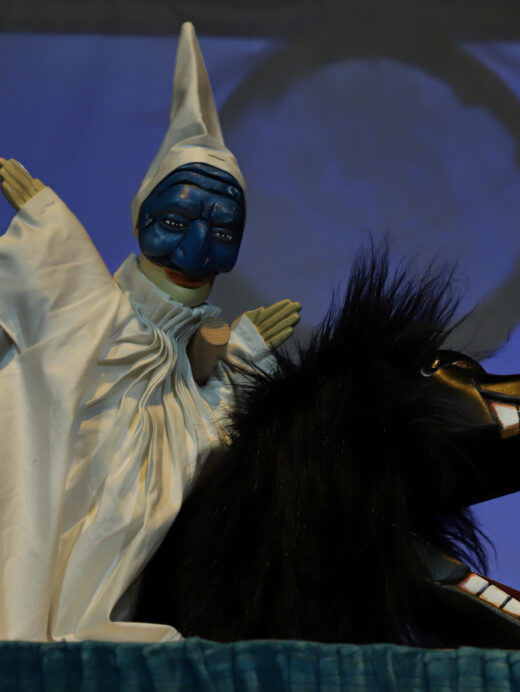 Une petite marionnette de Polichinelle à côté de la marionnette d'un monstre avec une grande gueule et des poils hérissés.
